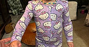 Athena is registered to the contest to win money with this photo: toddler, child, pajamas, hello_kitty, pacifier, beaded_necklace, hand_holding, barefoot, carpet, living_room, sofa, cushion, blanket, curtains, person, indoor, portrait, clothing, cute, baby
