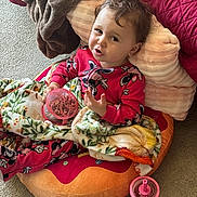Athena joined the competition — help win amazing prizes! toddler, child, pajamas, pink, blanket, cushion, donut_shaped_cushion, snack_container, sippy_cup, carpet, indoor, face, expression, cozy, soft_blanket, person, cute, relaxed, seated, home