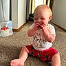 Kamden is registered to the contest to win money with this photo: baby, child, infant, sitting, carpet, clothing, shorts, shirt, happy, smiling, hands, feet, indoor, hallway, home, person, cute, celebration, red, white