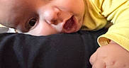 Mathéo participe au concours pour gagner de l'argent avec cette photo : baby, close_up, face, hand, yellow_clothing, curious_expression, infant, skin, person, child, cute, wide_eyes, mouth_open, resting, indoor, soft_light, human, portrait, small_hand, adorable