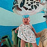 baby, child, smiling, blue_bow, dress, person, hand, underwater_mural, sea_turtle, coral, wall_art, colorful, happy, portrait, indoor, skin, headband, adult_hand, vibrant, cute