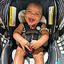 baby, car_seat, smiling, happy, infant, child, seatbelt, safety, black, striped, warning_label, clothing, hand, legs, indoor, cute, portrait, person, seat, bright