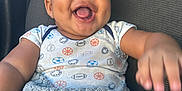 Madden is registered to the contest to win money with this photo: baby, child, smiling, happy, blanket, clothing, onesie, sports_theme, car_seat, seatbelt, infant, portrait, cute, face, skin, arm, hand, indoor, texture, comfort