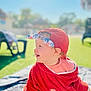baby, child, red_cap, headband, towel, outdoor, grass, sunny, smiling, side_view, infant, blanket, cute, portrait, happy, summer, daylight, nature, sitting, playful