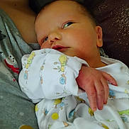 Wyatt is registered to the contest to win money with this photo: newborn, baby, infant, onesie, animal_print, hand, face, gaze, closeup, cuddling, adult, shirt, gray_shirt, holding, cute, sleepwear, soft, indoor, skin, portrait