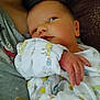newborn, baby, infant, onesie, animal_print, hand, face, gaze, closeup, cuddling, adult, shirt, gray_shirt, holding, cute, sleepwear, soft, indoor, skin, portrait