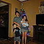 baby, barefoot, casual_clothing, child, children, christmas_tree, curtain, decorations, family, floor, furniture, group, holiday, indoor, living_room, portrait, sibling, smile, television, wood_floor
