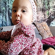 Giulia a rejoint le concours — aidez-le/la à gagner de superbes lots ! baby, child, headband, pink_bow, floral_dress, indoor, sofa, cushion, hand, person, portrait, closeup, face, young_child, wall_mural, waterfall, greenery, home, cozy, casual