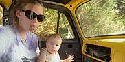 Eli joined the competition — help win amazing prizes! baby, child, woman, sunglasses, tongue_out, car_interior, yellow_car, vintage_car, forest, trees, daylight, casual_clothing, window, seat, person, portrait, playful, nature, sunlight, expression