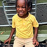 child, smiling, yellow_polo_shirt, braided_hair, vintage_car, land_rover, green_vehicle, beige_pants, sitting, outdoor, portrait, happy, vehicle_grille, front_bumper, casual_clothing, young_child, daylight, close_up, person, transport