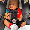 Tayvontae joined the competition — help win amazing prizes! baby, car_seat, infant, child, pacifier, red_shirt, white_sneakers, black_shorts, seat_belt, curly_hair, indoor, sitting, child_safety, cute, expression, young_child, footwear, clothing, person, close_up