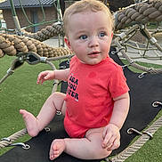 Kohen joined the competition — help win amazing prizes! baby, blue_eyes, casual_clothing, child, curly_hair, cute, daylight, expression, green_turf, infant, metal_rings, outdoor, person, playground, playtime, red_onesie, rope_swing, ropes, sitting, toddler