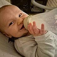 Noé participe au concours pour gagner de l'argent avec cette photo : baby, bottle, milk, smile, infant, clothing, hand, face, person, indoor, furniture, radiator, seat, happy, child, cozy, young, feeding, skin, closeup