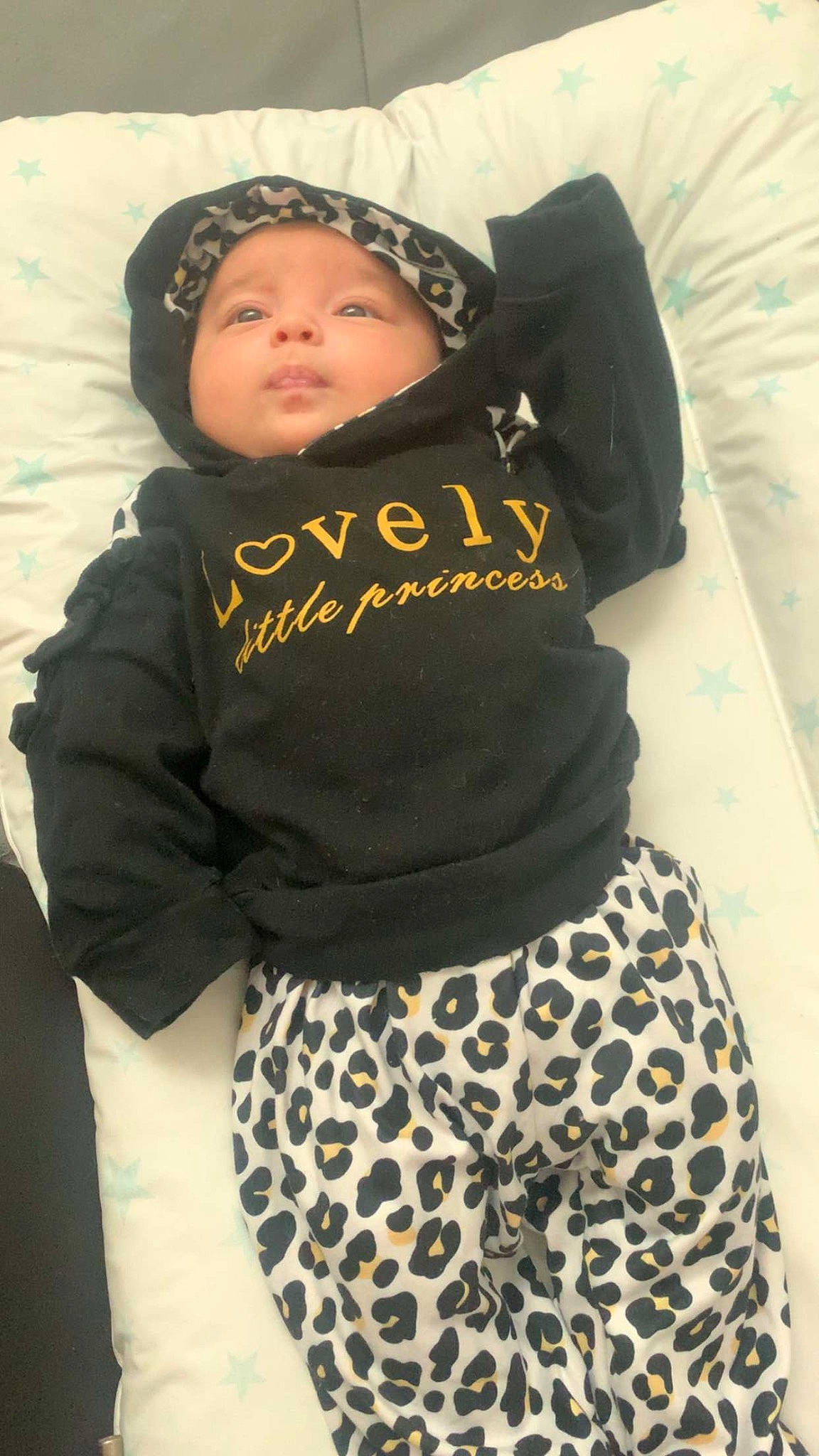 Maëlys participe au concours pour gagner de l'argent avec cette photo : baby, baby_products, baby_toddler_clothing, beanie, black, child, comfort, eye, fashion_accessory, fur, hood, hoodie, linens, pattern, person, personal_protective_equipment, sitting, sleeve, smile, t_shirt