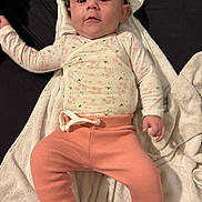 Lou participe au concours pour gagner de l'argent avec cette photo : baby, infant, child, towel, clothing, onesie, pants, pink, white, floral_pattern, laying_down, indoor, cute, soft_texture, face, person, young_child, smiling, sleepwear, comfortable