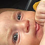 Lara participe au concours pour gagner de l'argent avec cette photo : baby, close_up, face, eyes, skin, hand, fingers, infant, portrait, curious, soft_lighting, mustard_clothing, young_child, cute, expression, human, child, innocence, newborn, cozy