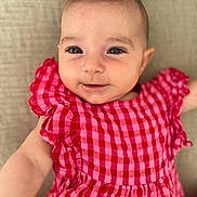 Lara participe au concours pour gagner de l'argent avec cette photo : baby, infant, child, smiling, face, dress, red, pink, checkered, pattern, cute, closeup, portrait, skin, eyes, babyclothing, adorable, person, lying, background