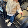 child, toddler, car, steering_wheel, sunglasses, sweater, jeans, shoes, seat, leather, interior, portrait, cute, fashion, standing, person, baby, casual, indoor, vehicle