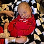 baby, newborn, sleeping, blanket, red_clothing, onesie, white_socks, tattoo, hand, indoor, cozy, comfort, peaceful, infant, cute, soft, rest, black_and_white, checkered_pattern, portrait