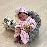 Celine Jade is registered to the contest to win money with this photo: baby, sleeping, pink_robe, towel_turban, small_chair, iced_coffee, starbucks, miniature_laptop, vintage_camera, side_table, wooden_floor, indoors, cute, relaxed, hand_held, footwear_free, modern, cozy, portrait, child