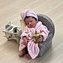 baby, sleeping, pink_robe, towel_turban, small_chair, iced_coffee, starbucks, miniature_laptop, vintage_camera, side_table, wooden_floor, indoors, cute, relaxed, hand_held, footwear_free, modern, cozy, portrait, child