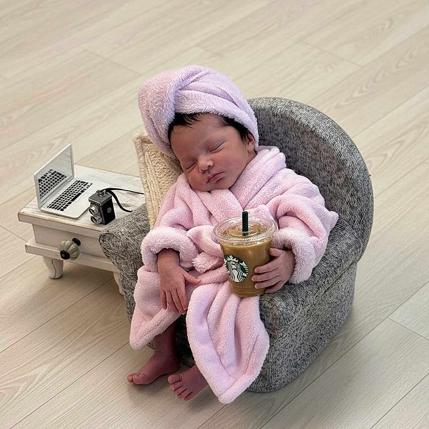 Celine Jade is registered to the contest to win money with this photo: baby, child, cozy, cute, footwear_free, hand_held, iced_coffee, indoors, miniature_laptop, modern, pink_robe, portrait, relaxed, side_table, sleeping, small_chair, starbucks, towel_turban, vintage_camera, wooden_floor