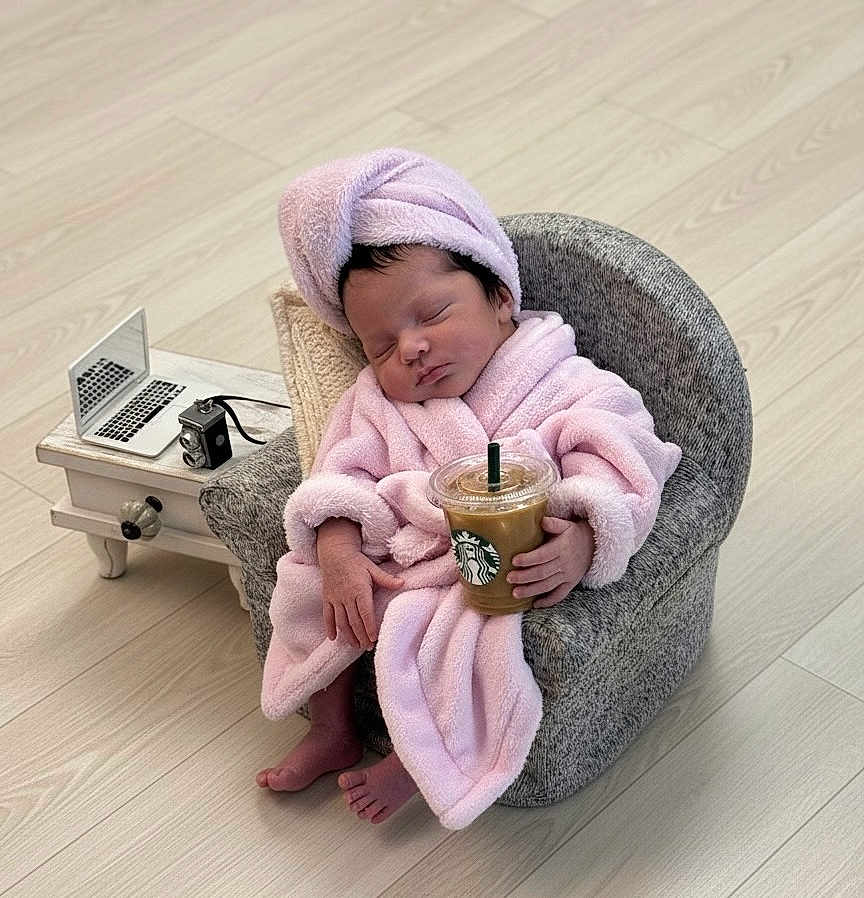 Celine Jade is registered to the contest to win money with this photo: baby, sleeping, pink_robe, towel_turban, small_chair, iced_coffee, starbucks, miniature_laptop, vintage_camera, side_table, wooden_floor, indoors, cute, relaxed, hand_held, footwear_free, modern, cozy, portrait, child