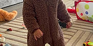 Arian joined the competition — help win amazing prizes! toddler, child, onesie, bear_costume, hat, indoor, living_room, rug, toy_car, stuffed_animal, floor, curious, baby, footwear, play_area, furniture, cozy, smile, person, home