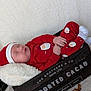 baby, sleeping, red_pajamas, santa_hat, wooden_crate, blanket, lantern, fairy_lights, autumn_leaves, holiday, festive, cozy, infant, cute, indoors, soft_texture, resting, peaceful, holiday_theme, decor