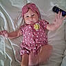 Emerald is registered to the contest to win money with this photo: baby, infant, pink_clothing, headband, polka_dot, blanket, remote_control, lying_down, cute, child, indoor, soft_lighting, playful, reaching_hand, portrait, smiling, baby_girl, comfortable, homedecor, person