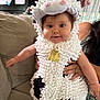 Madison joined the competition — help win amazing prizes! baby, child, costume, cow_costume, fluffy, indoor, person, cute, smile, face, arm, hand, couch, furniture, home, bell, black_and_white, fabric, soft, holding