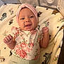Mia is registered to the contest to win money with this photo: baby, infant, smiling, headband, floral_clothing, blanket, animal_print, playpen, cute, happy, portrait, child, indoor, soft_texture, newborn, small_hands, toddler, comfortable, lying_down, pink