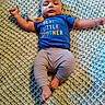 Auryn is registered to the contest to win money with this photo: baby, infant, child, lying_down, portrait, face, eyes, blue_shirt, striped_pants, crocheted_blanket, blanket, pacifier, clothing, indoor, home, relaxed, alert, photography, cute, sitting_area