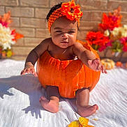 Isleya joined the competition — help win amazing prizes! baby, child, infant, portrait, sitting, orange_costume, pumpkin_costume, flower_crown, flowers, autumn, mini_pumpkins, brick_wall, outdoor, blanket, festive, seasonal, colorful, baby_photography, smiling, feet