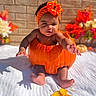 baby, child, infant, portrait, sitting, orange_costume, pumpkin_costume, flower_crown, flowers, autumn, mini_pumpkins, brick_wall, outdoor, blanket, festive, seasonal, colorful, baby_photography, smiling, feet