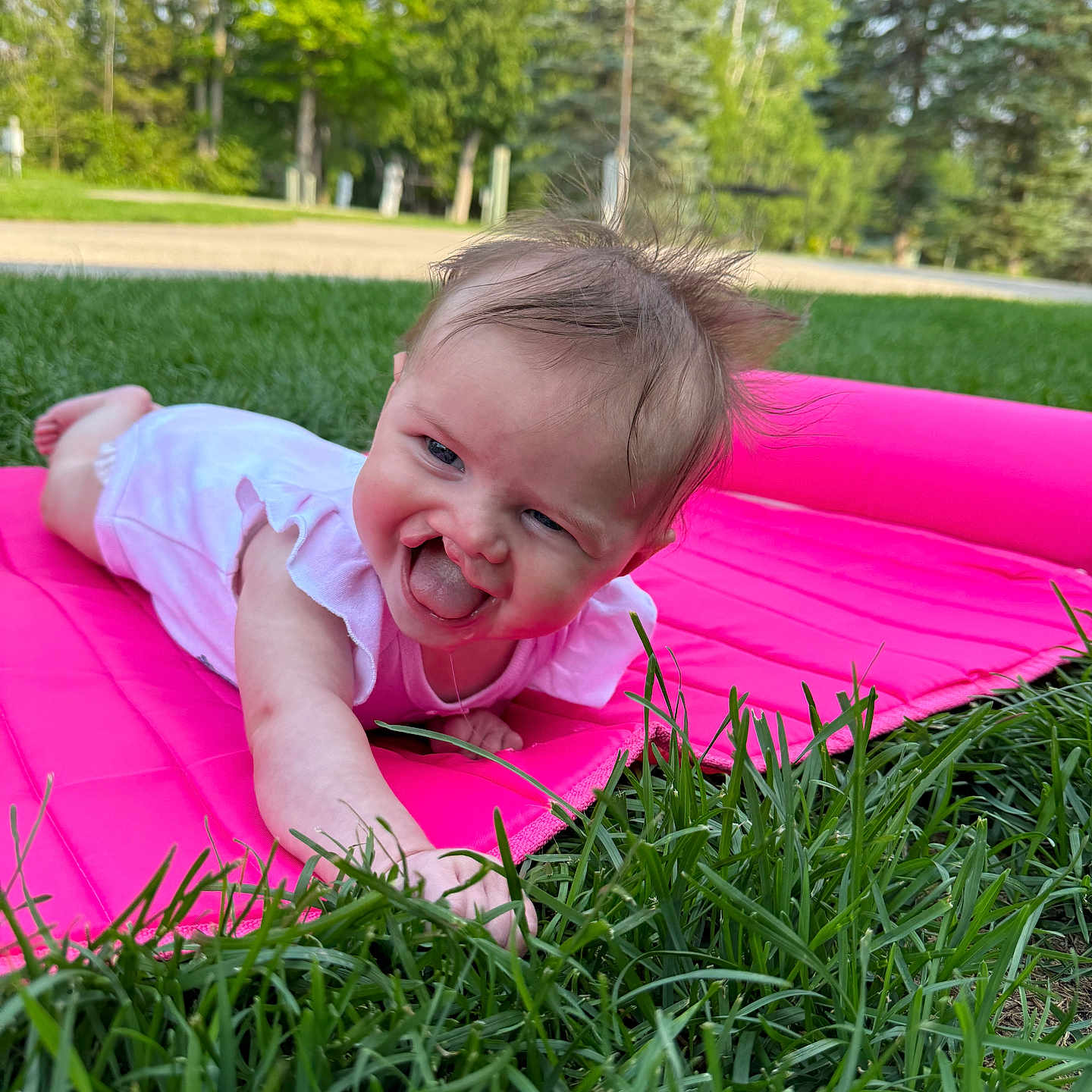 Clark joined the competition — help win amazing prizes! baby, casual_clothing, child, cute, daylight, grass, grass_blades, greenery, happy, infant, nature, outdoor, park, person, pink_mat, playful, smiling, summer, toddler, tongue_out