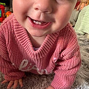 Lilianna is registered to the contest to win money with this photo: baby, child, infant, smiling, toothy_smile, crawling, portrait, close_up, pink_sweater, knitwear, indoor, living_room, rug, plush_rug, stuffed_toy, toy, happy, face, hands, home