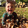Lilianna is registered to the contest to win money with this photo: baby, child, smiling, laughing, outdoor, autumn, leaves, fall, bow, headband, floral_clothing, green_outfit, portrait, garden, backyard, firewood, trees, sunlight, happy, closeup