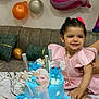 child, toddler, birthday_cake, frozen_theme, blue_cake, balloons, pink_dress, smiling, party, celebration, sofa, cushions, table, decorations, snowflakes, happy, indoors, cake_decoration, person, festive
