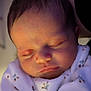 newborn, baby, infant, sleeping, face, head, swaddled, pajamas, floral_pattern, close_up, portrait, peaceful, cute, soft_lighting, eyelashes, lips, nose, skin, hair, indoors