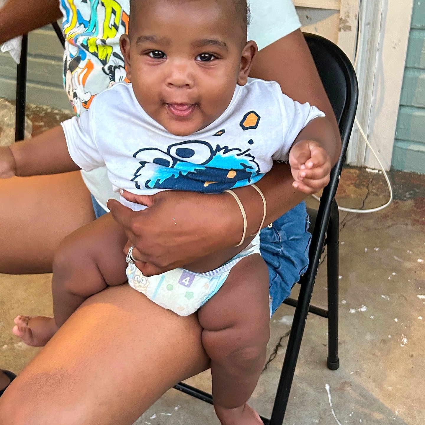 Robert is registered to the contest to win money with this photo: adult, baby, casual, chair, child, clothing, concrete, diaper, door, foot, hand, holding, outdoor, person, playful, shirt, sitting, smiling, toddler, wall