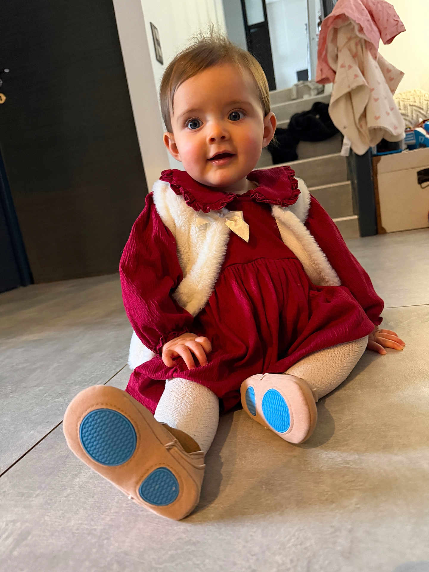 Lola a rejoint le concours — aidez-le/la à gagner de superbes lots ! toddler, child, floor, red_dress, white_vest, blue_sole_shoes, indoor, stairs, curious, smiling, person, young_child, home_interior, clothing, sitting, portrait, cute, baby, floor_tiles, warm_lighting