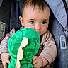 Ezio participe au concours pour gagner de l'argent avec cette photo : baby, child, plush_dinosaur, green_toy, car_seat, cute, infant, soft_lighting, innocence, curious_eyes, clothing, cuddly_toy, seated, portrait, young_child, indoor, closeup, hands, face, toddler