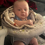 Dylan is registered to the contest to win money with this photo: baby, blanket, baby_seat, child, indoor, cute, infant, face, person, clothing, furniture, patterned, comfort, skin, expression, curly_hair, relaxing, home, soft, young