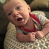 baby, infant, face, expression, curious, spiky_hair, onesie, red_collar, cushion, patterned, soft_focus, indoor, closeup, child, skin, hands, lying_down, portrait, cute, wide_eyes