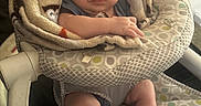 Dylan is registered to the contest to win money with this photo: arms, baby, baby_seat, blanket, child, closeup, comfort, curious, cute, expression, face, human, indoor, infant, legs, patterned_fabric, seated, skin, small, soft_texture
