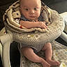 baby, blanket, baby_seat, infant, child, face, legs, arms, patterned_fabric, indoor, cute, seated, soft_texture, curious, skin, human, closeup, comfort, expression, small