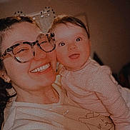 Mayleigh is registered to the contest to win money with this photo: woman, baby, glasses, braid, smile, happy, indoor, portrait, person, child, holding, light, cozy, face, cute, apparel, family, love, joy, warm