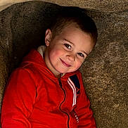 Lorenzo joined the competition — help win amazing prizes! child, boy, red_hoodie, smile, face, portrait, rock, cave, outdoor, casual_clothing, young, happy, cute, cozy, natural_light, head_and_shoulders, brown_hair, eyebrows, cheeks, zipper