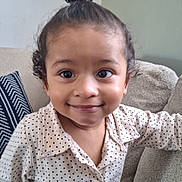 Dylan participe au concours pour gagner de l'argent avec cette photo : background, child, comfort, couch, cushion, cute, face, hairstyle, happy, home, indoor, person, polka_dot, portrait, seated, shirt, smiling, toddler, top_bun, young_child